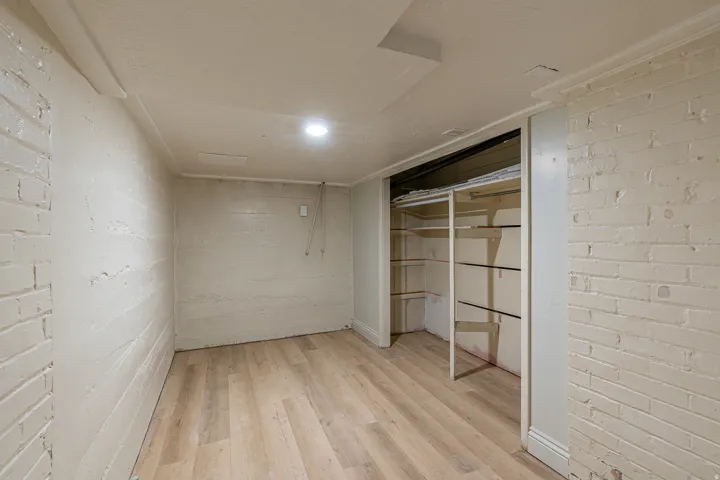 Unfurnished bedroom with brick wall, light wood-style floors, a closet, and concrete block wall