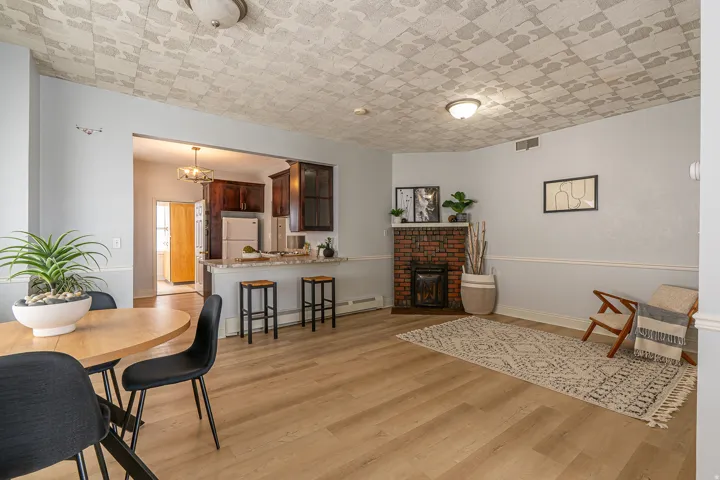Dining room with a baseboard heating unit, light wood-type flooring, a brick fireplace, and a chandelier