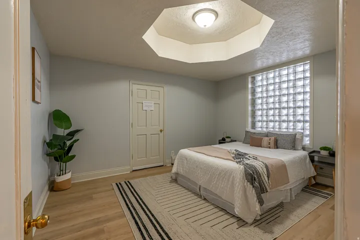 Bedroom with a textured ceiling, light wood-type flooring, and baseboard heating