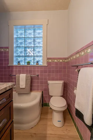 Full bath featuring a garden tub, wainscoting, vanity, light wood-style flooring, and tile walls