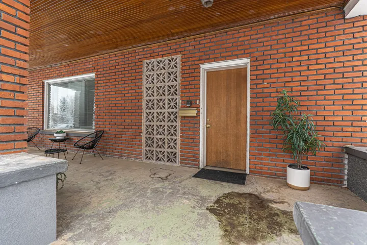 Property entrance featuring brick siding and a patio area