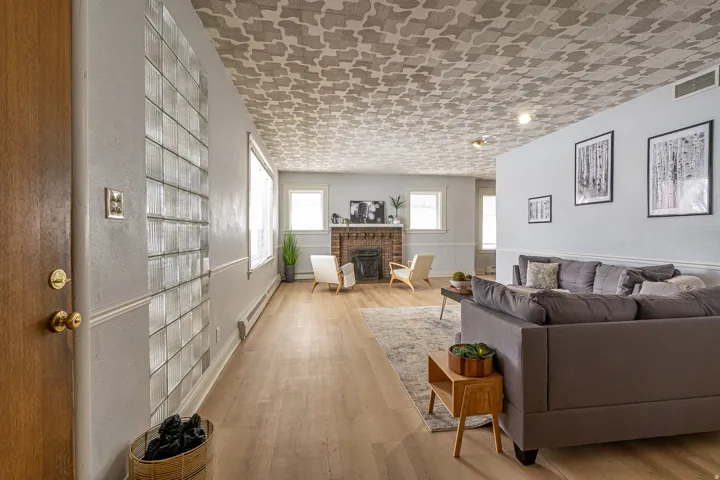 Living area featuring light wood-style floors, a baseboard radiator, and a brick fireplace