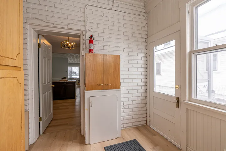 Doorway to outside featuring brick wall, wood finished floors, and a chandelier