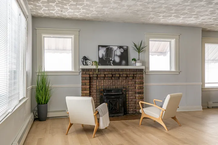 Living area with a baseboard heating unit, wood finished floors, and a brick fireplace
