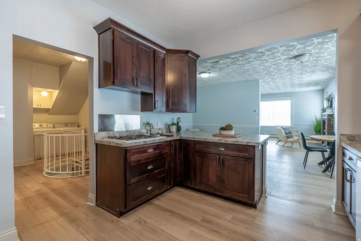 Kitchen with dark brown cabinets, light countertops, a peninsula, light wood-style flooring, and independent washer and dryer