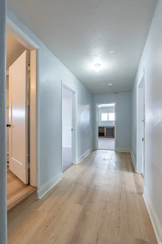 Corridor with a textured ceiling and light wood finished floors