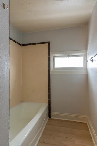Full bathroom with light wood-style flooring and bathing tub / shower combination