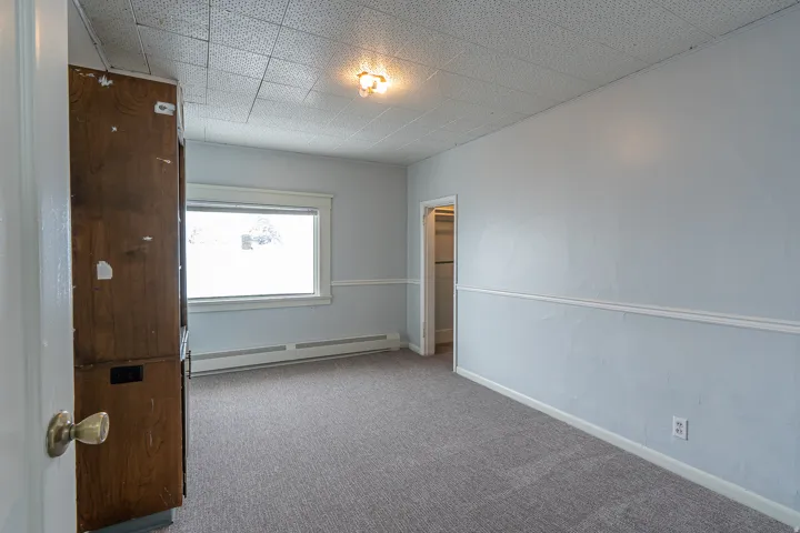 Unfurnished bedroom featuring a baseboard radiator and carpet floors
