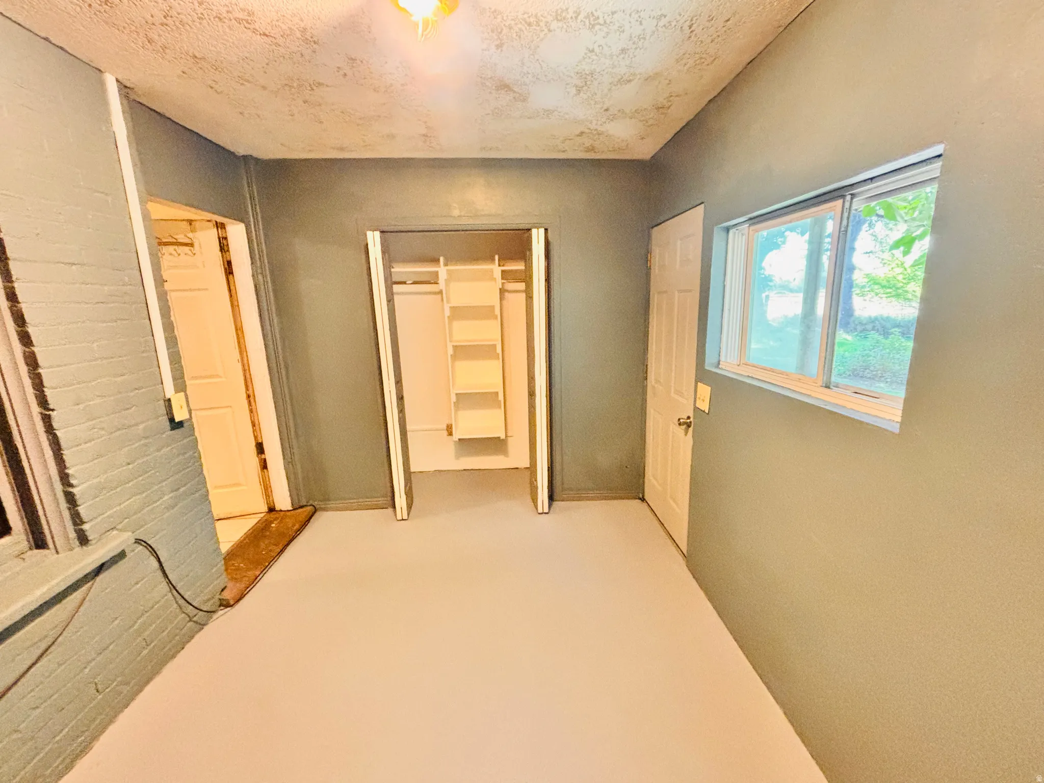 Integrated shelving system, recessed ceiling light, paneled doors, painted brick wall, and a window providing natural illumination