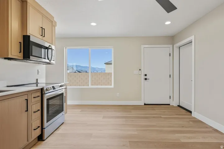 Kitchen featuring appliances with stainless steel finishes, light brown cabinets, light wood finished floors, recessed lighting, and light stone counters