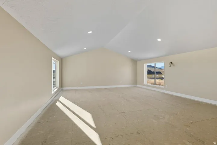 Empty room featuring healthy amount of natural light and lofted ceiling