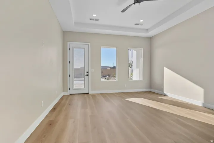 Entryway with light wood-type flooring, a ceiling fan, a raised ceiling, and recessed lighting