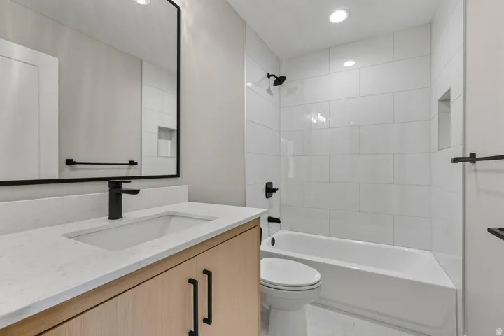 Bathroom with washtub / shower combination, vanity, and recessed lighting