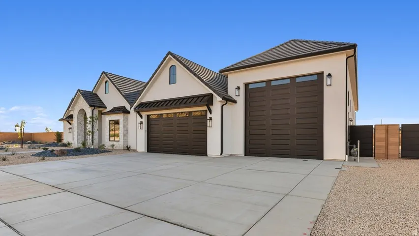 View of front of home with an attached garage, a standing seam roof, a metal roof, driveway, and stucco siding