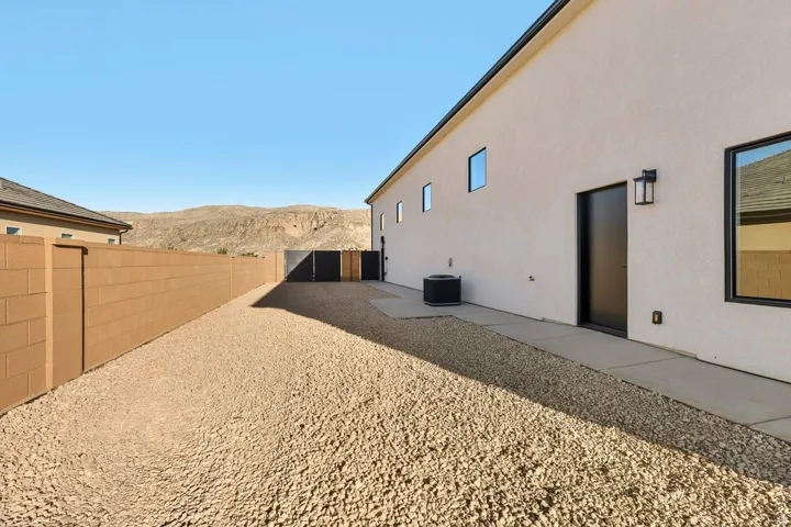 View of side of home featuring a mountain view, a fenced backyard, stucco siding, and a patio area
