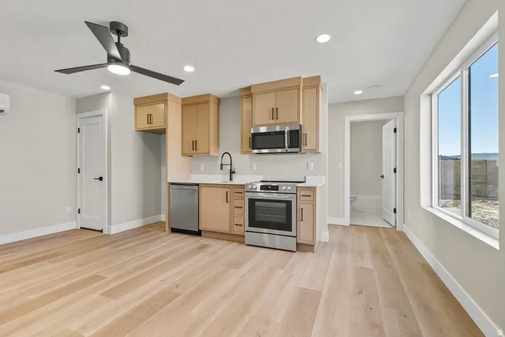 Kitchen with stainless steel appliances, light countertops, light brown cabinetry, light wood-style flooring, and recessed lighting