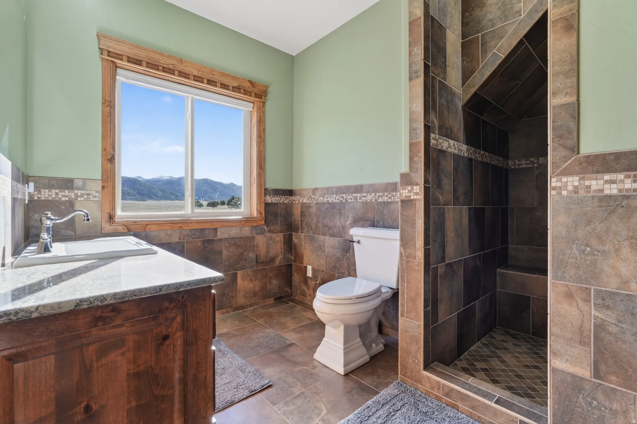 Full bathroom featuring vanity, wainscoting, tile walls, and a shower stall