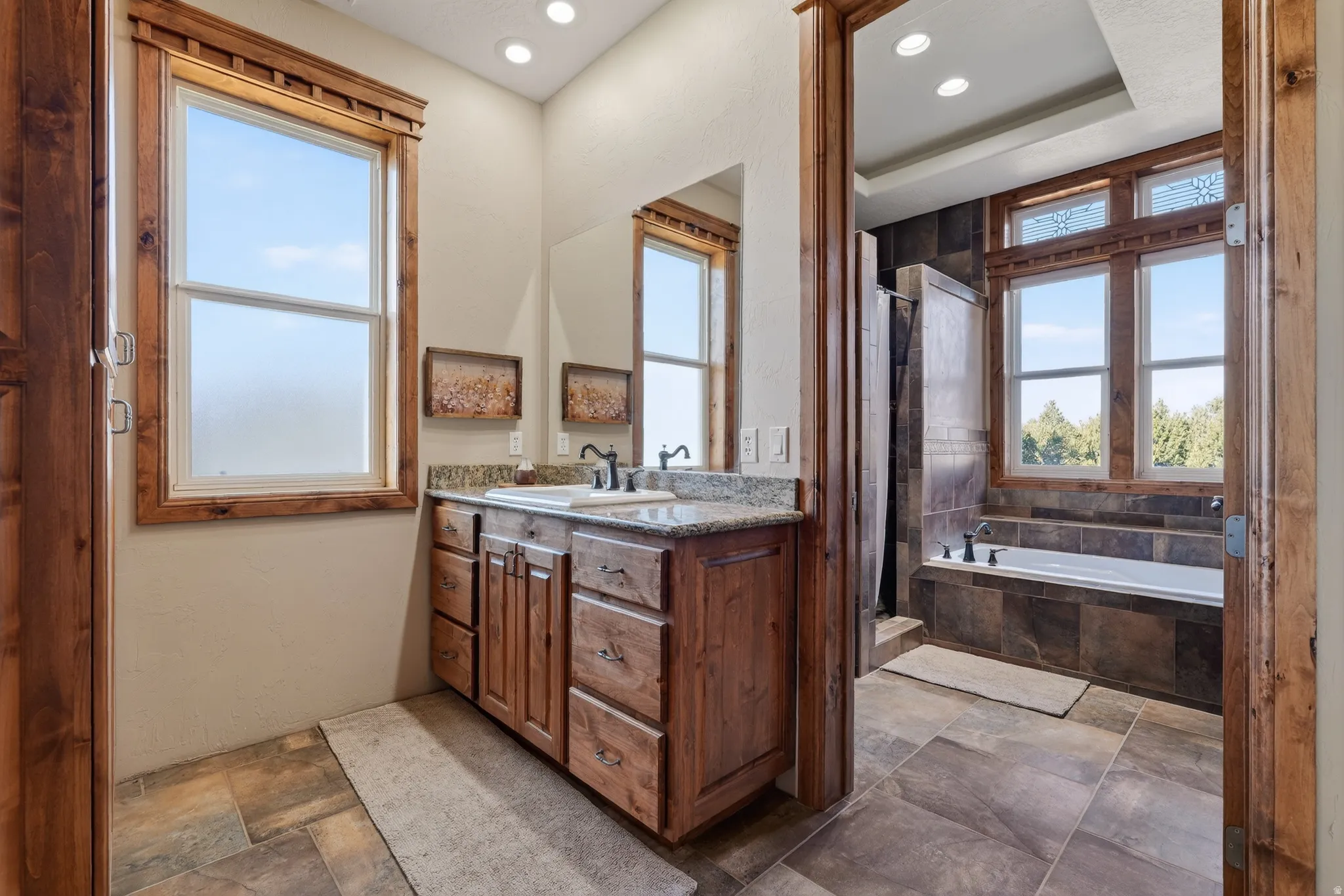 Bathroom with a bath, stone tile flooring, vanity, a stall shower, and recessed lighting