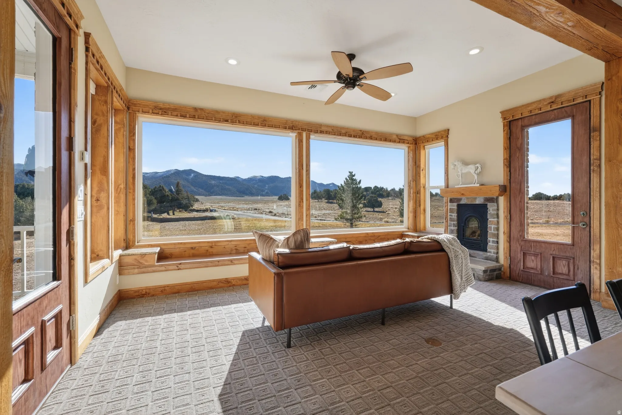 Living area with a mountain view, a fireplace, healthy amount of natural light, and a ceiling fan