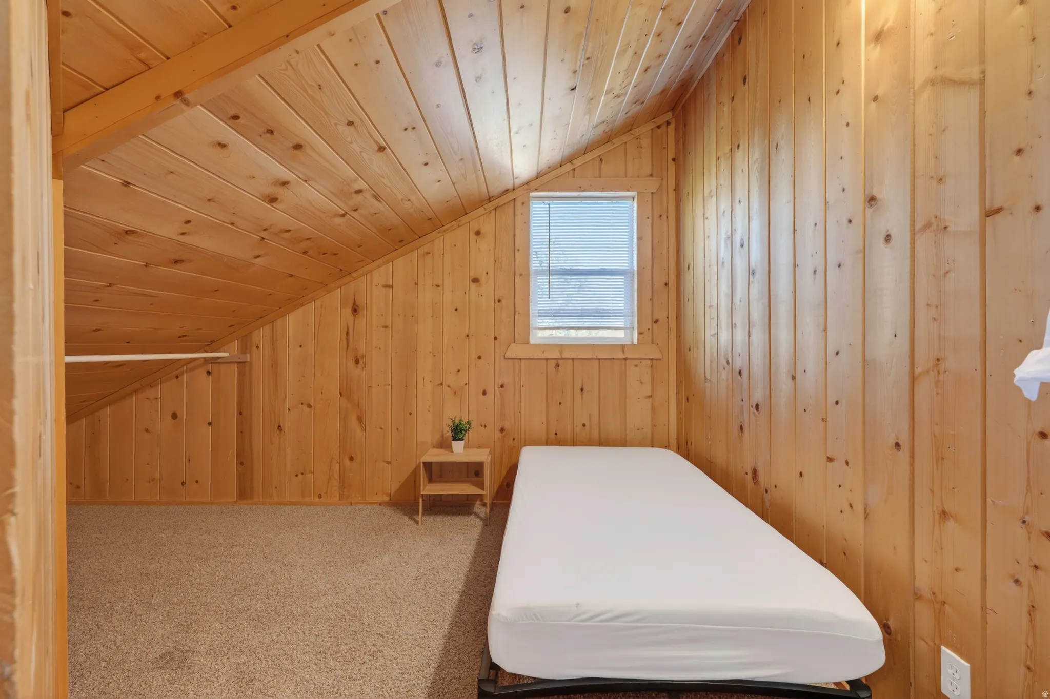 Bedroom featuring wooden walls, wooden ceiling, vaulted ceiling, and carpet