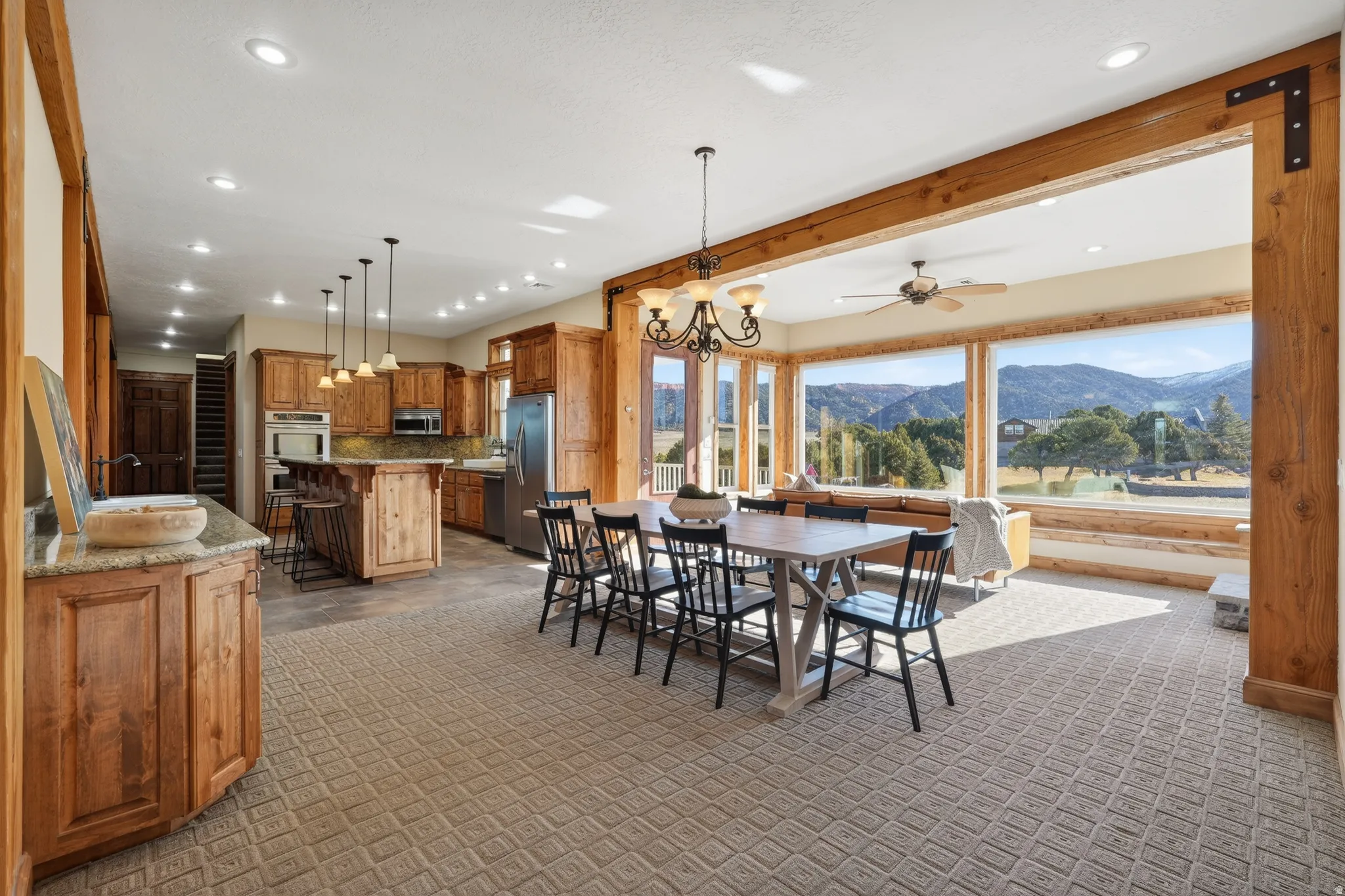 Dining area with a chandelier, a mountain view, light carpet, a ceiling fan, and recessed lighting
