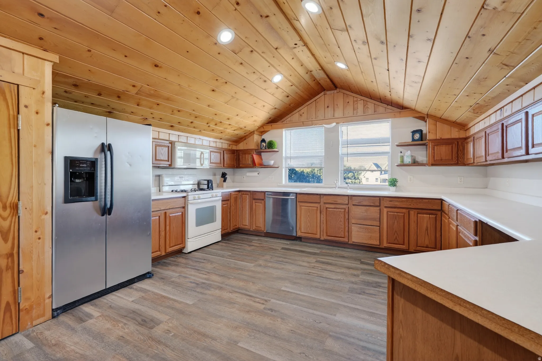 Kitchen with open shelves, wood ceiling, stainless steel appliances, light countertops, and brown cabinets