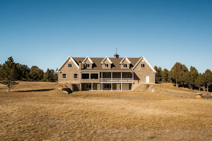 Back of property with covered porch, a yard, and a chimney
