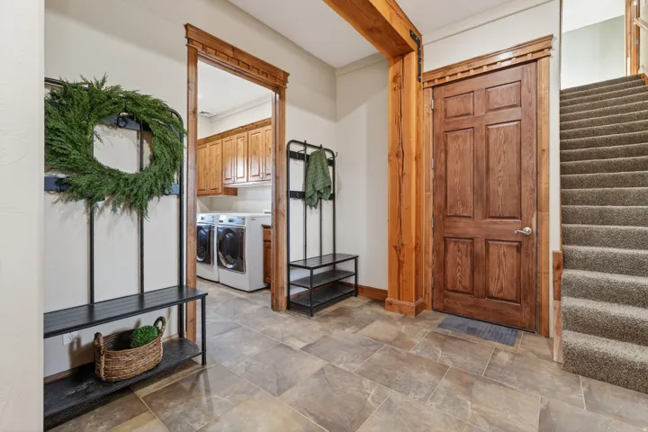 Entrance foyer featuring stairway, washing machine and dryer, and stone finish flooring