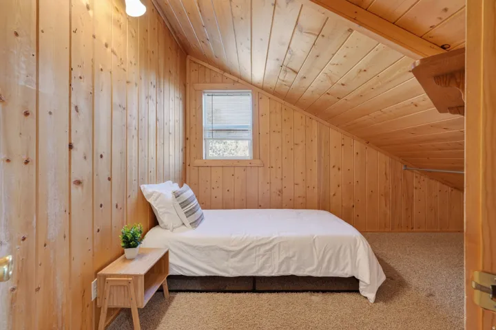 Carpeted bedroom with wooden walls, wood ceiling, and vaulted ceiling