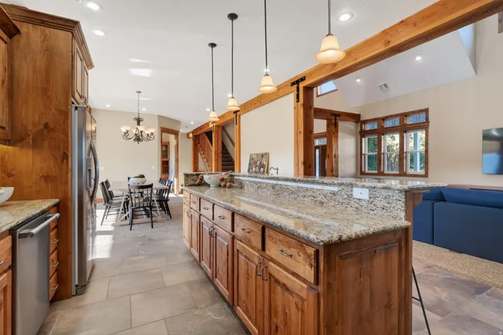 Kitchen with brown cabinets, pendant lighting, light stone counters, a breakfast bar area, and open floor plan
