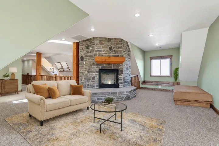 Carpeted living area with a stone fireplace and recessed lighting
