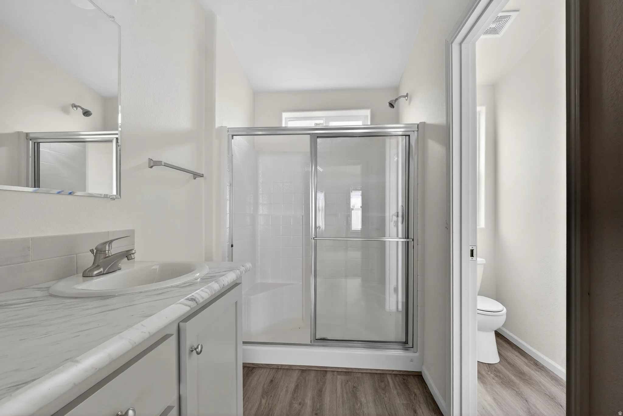 Bathroom featuring vanity, a shower stall, and light wood-type flooring