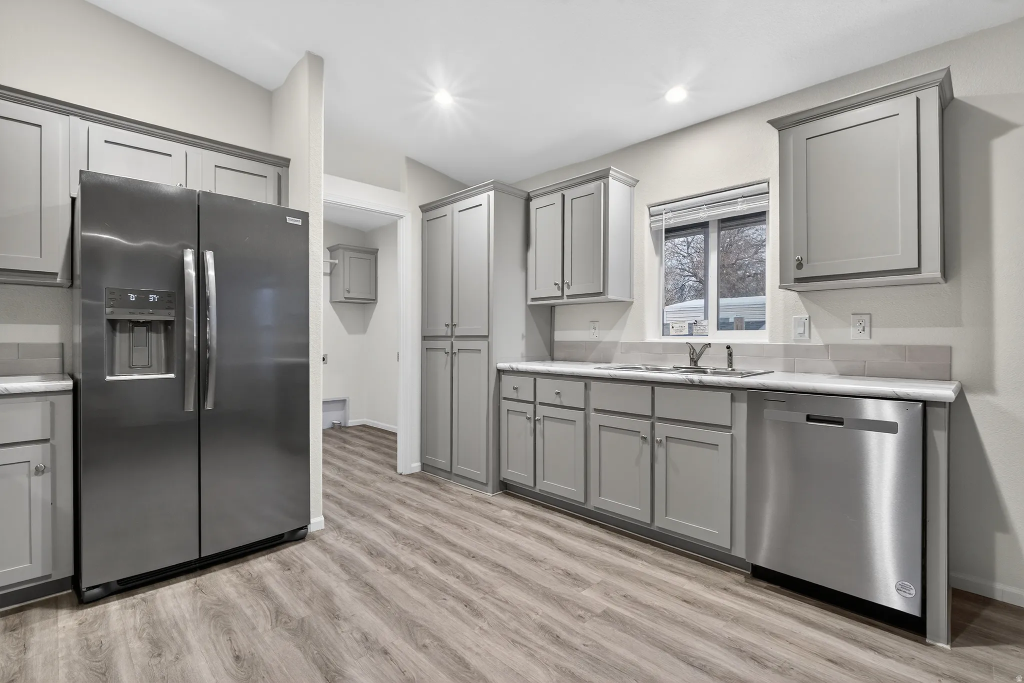Kitchen with gray cabinets, stainless steel appliances, light wood-type flooring, and recessed lighting
