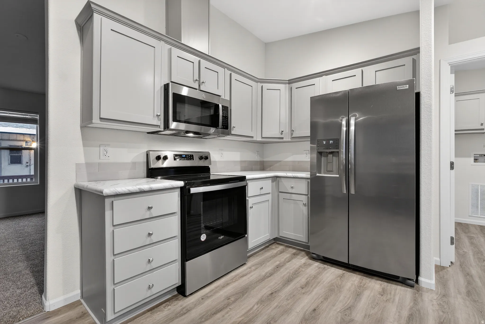 Kitchen with appliances with stainless steel finishes, gray cabinetry, and light countertops