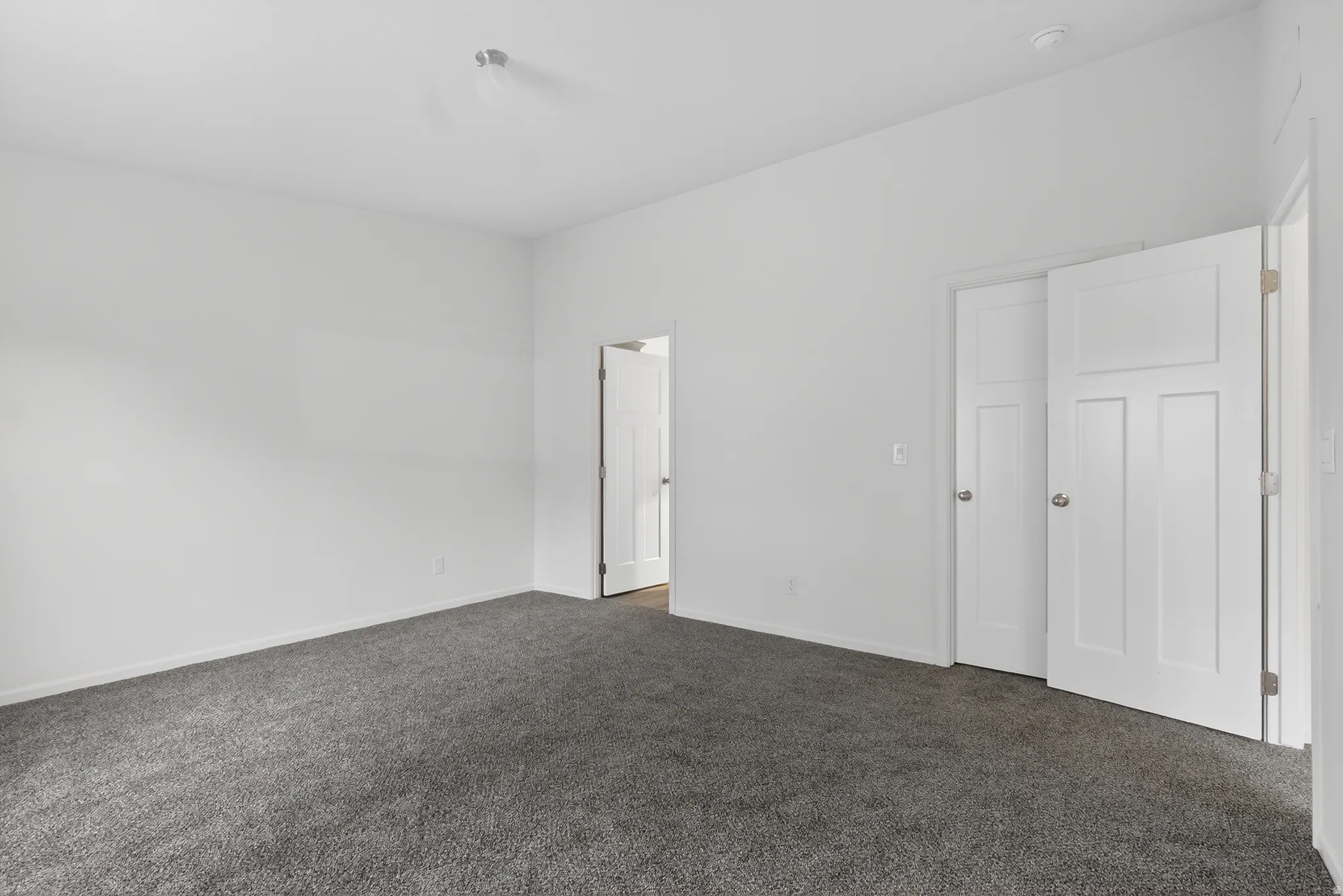 Unfurnished bedroom with dark carpet and baseboards