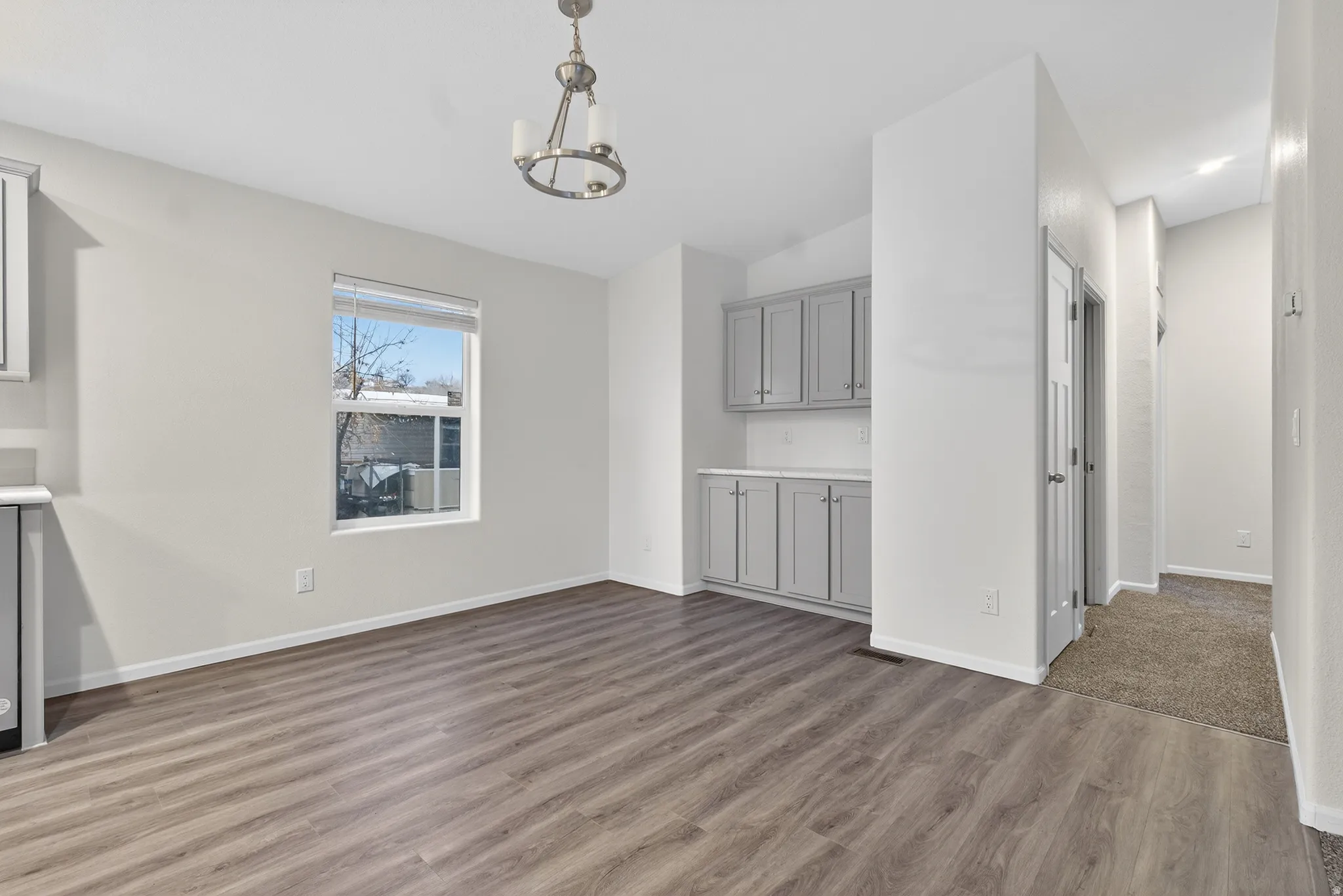 Unfurnished living room featuring wood finished floors, a chandelier, and lofted ceiling
