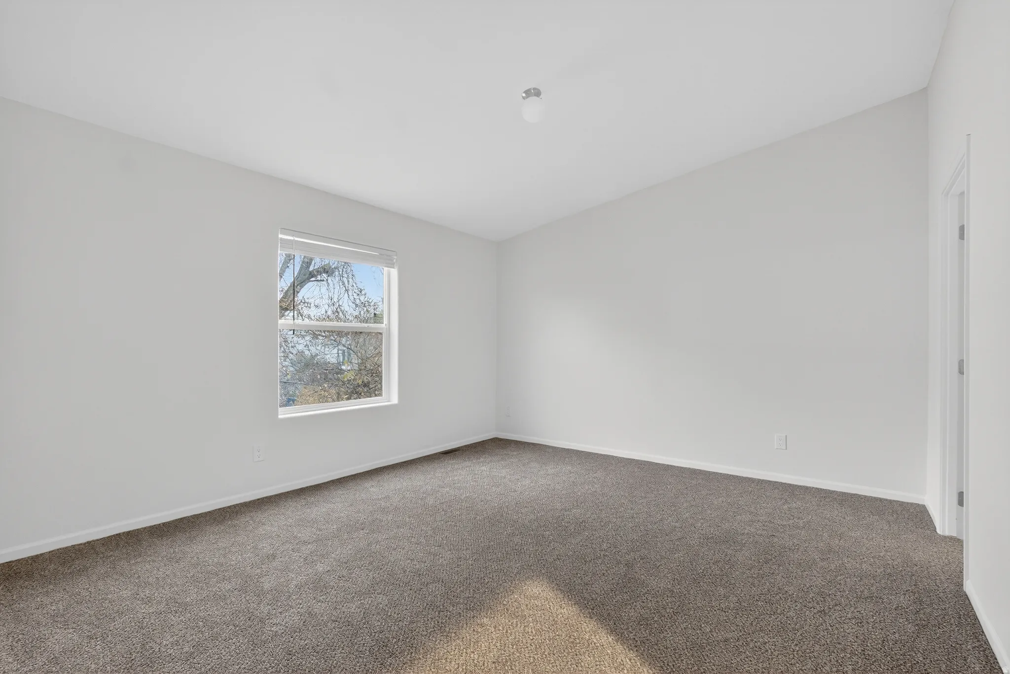 Carpeted spare room featuring baseboards