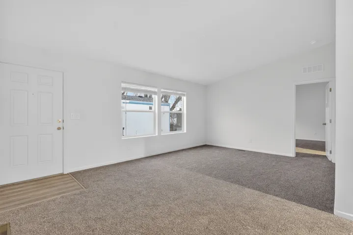 Carpeted spare room featuring vaulted ceiling and baseboards