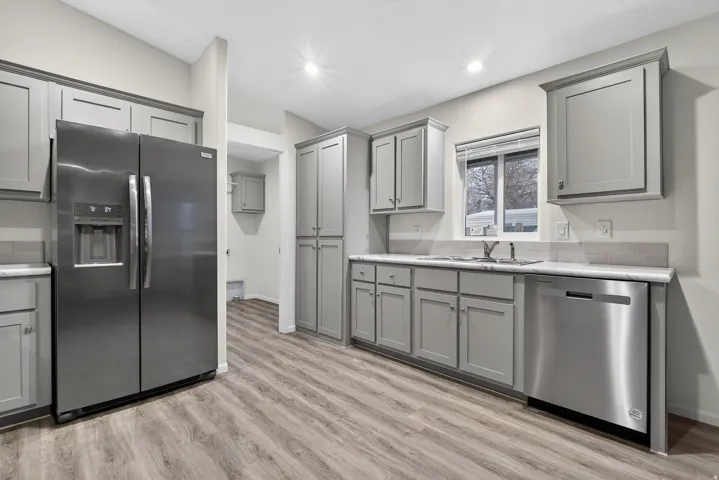 Kitchen with gray cabinets, stainless steel appliances, light wood-type flooring, and recessed lighting