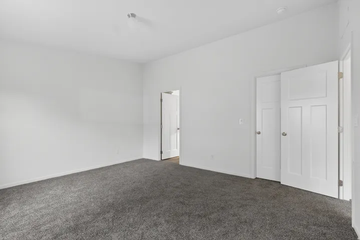 Unfurnished bedroom with dark carpet and baseboards
