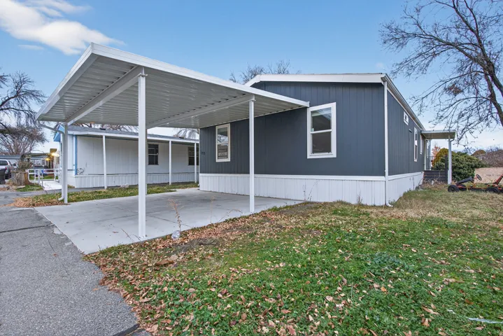 View of front of property featuring a front lawn, a carport, concrete driveway, and a patio