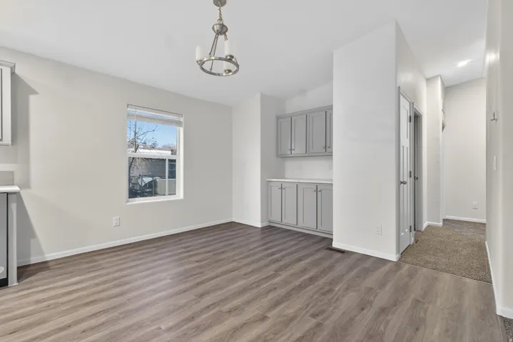 Unfurnished living room featuring wood finished floors, a chandelier, and lofted ceiling