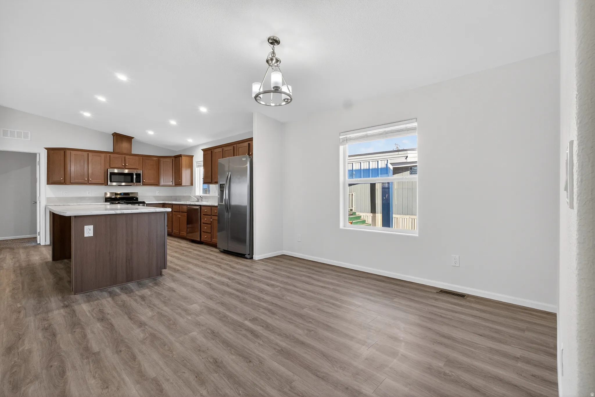 Kitchen with light countertops, vaulted ceiling, stainless steel appliances, recessed lighting, and decorative light fixtures