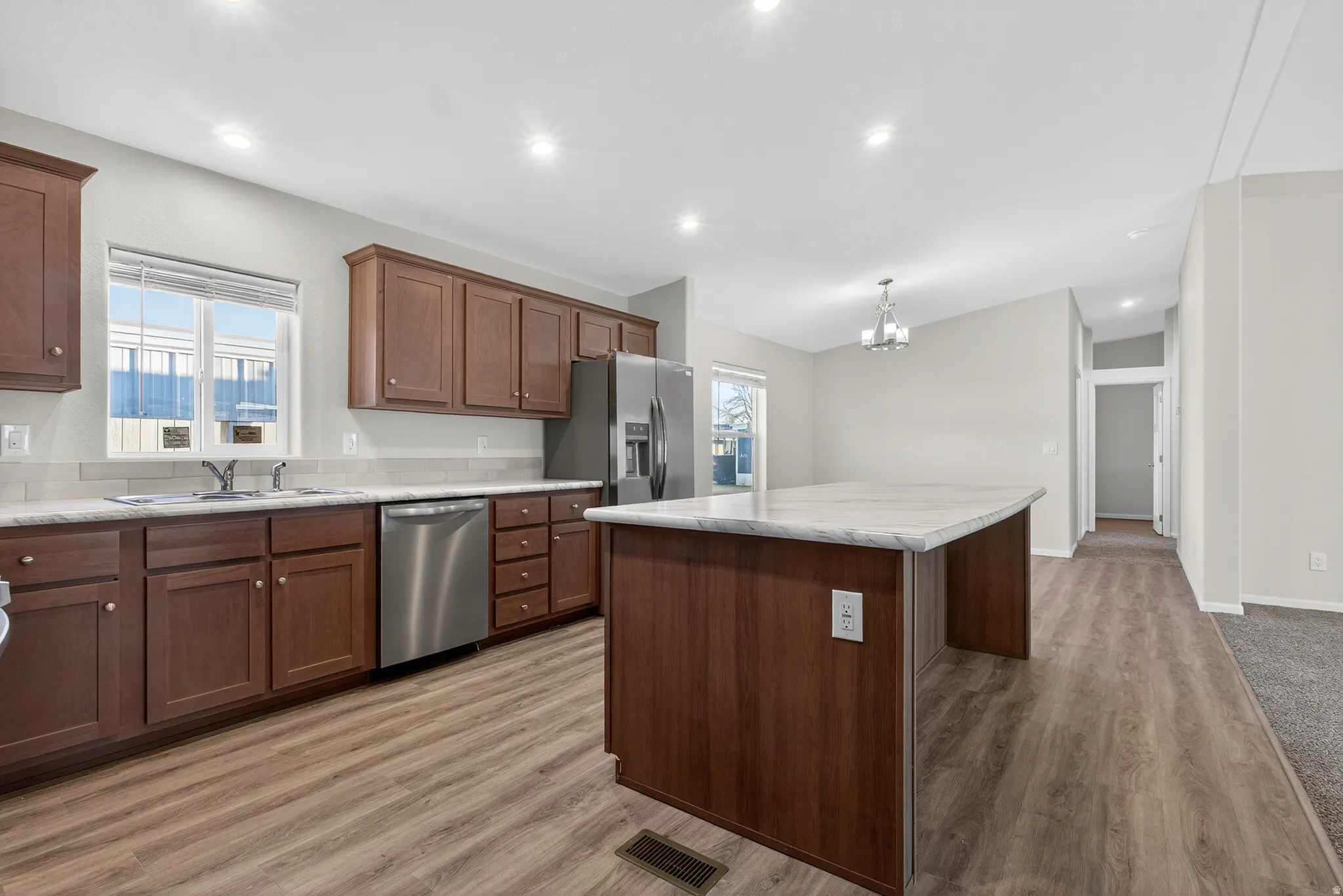 Kitchen with a center island, appliances with stainless steel finishes, a chandelier, light wood-style flooring, and recessed lighting