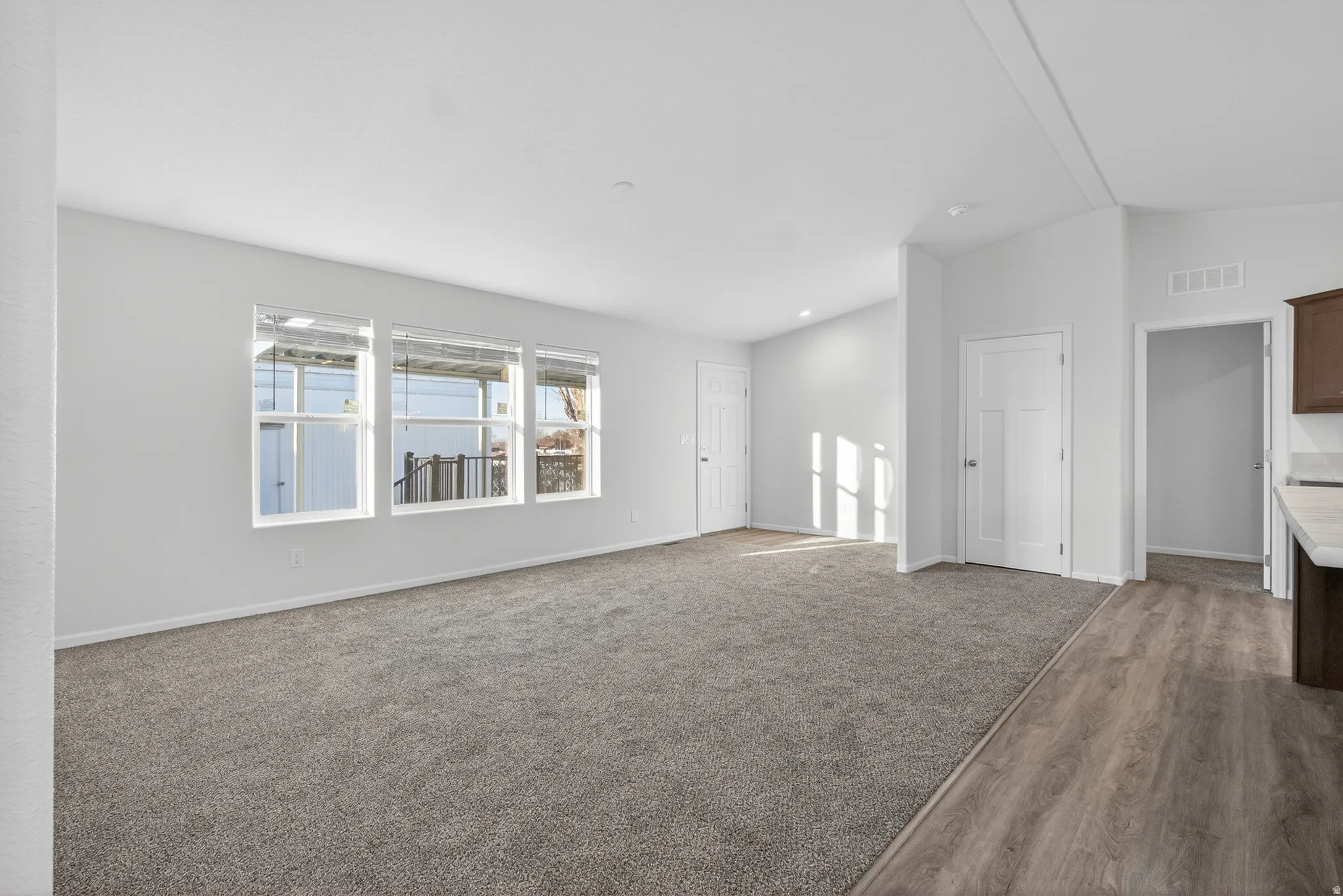 Unfurnished living room featuring lofted ceiling, carpet flooring, and wood finished floors