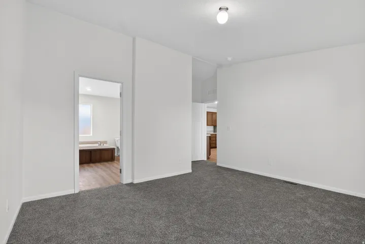 Unfurnished bedroom with connected bathroom and carpet flooring