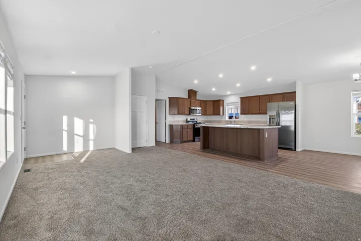 Kitchen with open floor plan, light countertops, dark colored carpet, appliances with stainless steel finishes, and lofted ceiling