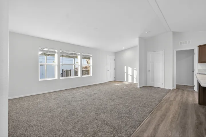 Unfurnished living room featuring lofted ceiling, carpet flooring, and wood finished floors