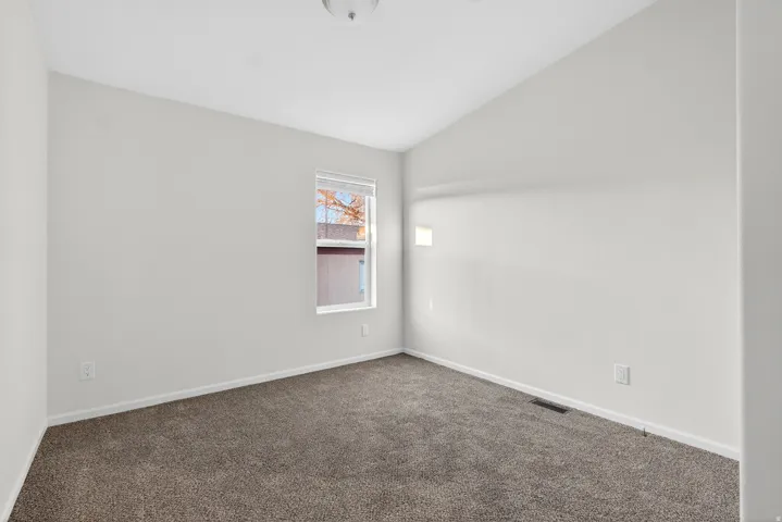 Empty room featuring vaulted ceiling and carpet flooring