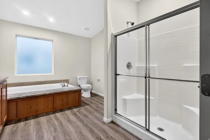 Bathroom with a stall shower, vanity, a bath, and light wood-style flooring